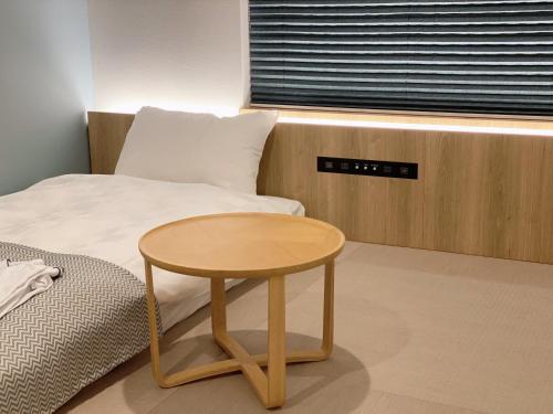 uma pequena mesa de madeira ao lado de uma cama em THE TOURIST HOTEL & Cafe AKIHABARA em Tóquio