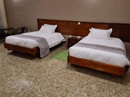 two beds in a hotel room with a green rug at Bunyonyi Overland Resort in Kabale