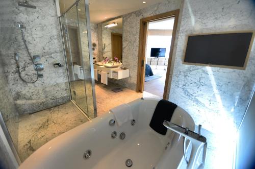 a bathroom with a tub and a tv and a shower at Wyndham Grand Istanbul Levent Hotel & Conference Center in Istanbul