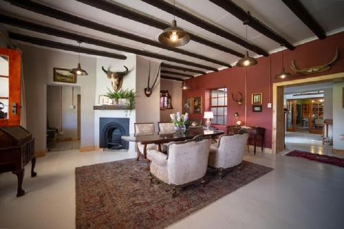 a living room with a table and chairs and a fireplace at Kamagu Safari Lodge in Touwsrivier