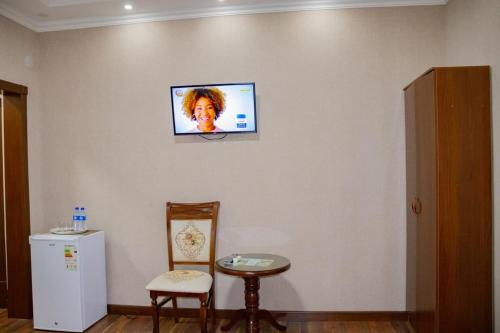 a tv on a wall in a room with a table and chairs at Euro Asia Hotel in Samarkand