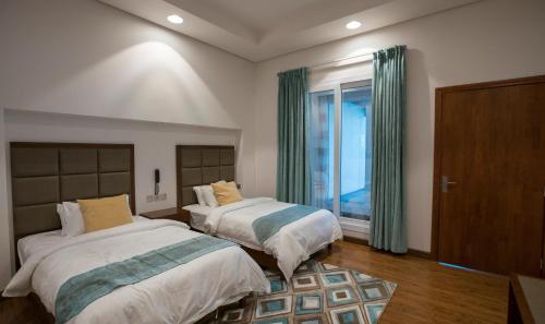 a bedroom with two beds and a window at Asahalah Farm Pool Villas in Seeb