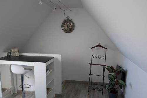 Zimmer mit einem Schreibtisch und einer Uhr an der Wand in der Unterkunft Duplex charmant idéalement situé in Dole