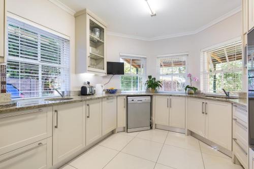 a large kitchen with white cabinets and windows at Rustic Manor Guest House in Tokai
