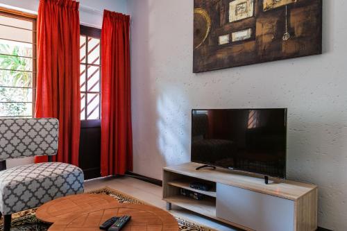 a living room with a television and red curtains at Bedfordview Haven in Johannesburg