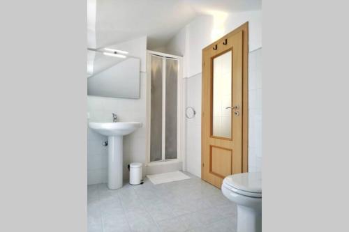 uma casa de banho com um WC, um lavatório e uma porta em La Terrazza sul Mare em Loano