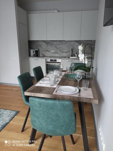 a kitchen with a wooden table with green chairs at NEW BIG LOFT APARTMENTS JURMALA with FREE SECURED PARKING in Jūrmala