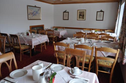 ein Esszimmer mit Tischen und Stühlen sowie weißen Gerichten in der Unterkunft Hotel Tauernpasshöhe in Obertauern