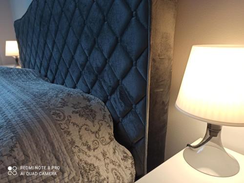 a bed with a blue headboard next to a lamp at NEW BIG LOFT APARTMENTS JURMALA with FREE SECURED PARKING in Jūrmala