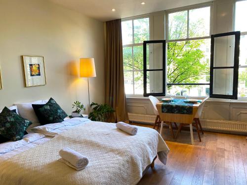 um quarto com uma cama, uma secretária e janelas em The Canalview Retreat em Amsterdã