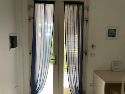 a sliding glass door with blue curtains in a room at Le stanze di chiara in Torre Lapillo
