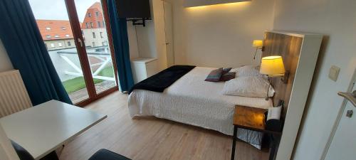ein Schlafzimmer mit einem Bett und einem großen Fenster in der Unterkunft Hotel La Cascada in Bredene