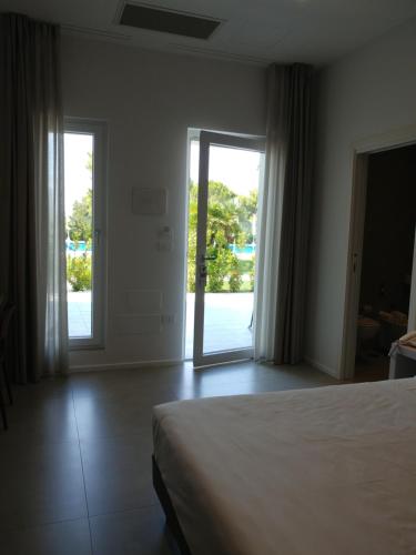 a bedroom with a bed and a sliding glass door at SALAPIA SALIS RESORT in Margherita di Savoia