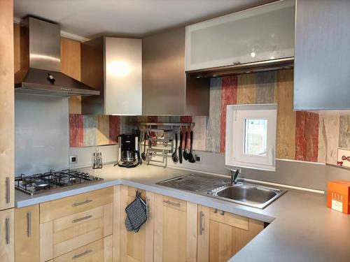 - une cuisine avec des placards en bois, un évier et une cuisinière dans l'établissement PAVILLON DU GARDE CHASSE, à Bugnicourt