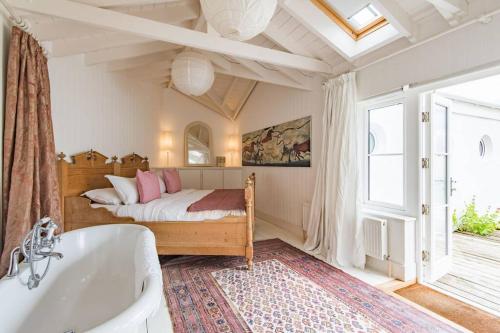 ein Schlafzimmer mit einem Bett und einer Badewanne und einem Fenster in der Unterkunft Trafalgar Cottage - Stunning sea view property on beach in Kingsdown