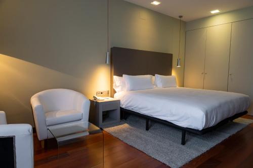 a bedroom with a white bed and a chair at Hotel AR Isabel de Farnesio in La Granja de San Ildefonso