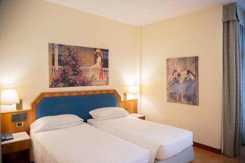 Cette chambre d'hôtel comprend 2 lits et des peintures murales. dans l'établissement iH Hotels Milano Eur - Trezzano sul Naviglio, à Trezzano sul Naviglio