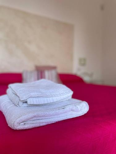 a stack of white towels sitting on a red bed at Le stanze di chiara in Torre Lapillo