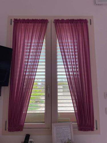 a window with pink curtains in a room at Le stanze di chiara in Torre Lapillo
