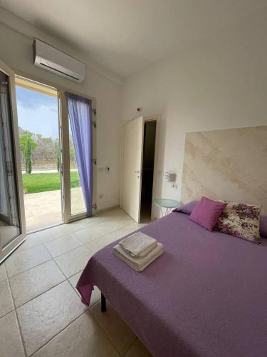 a bedroom with a purple bed and a large window at Le stanze di chiara in Torre Lapillo