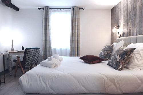 a bedroom with a large white bed and a desk at Hôtel La Grange Aux Marmottes in Viscos