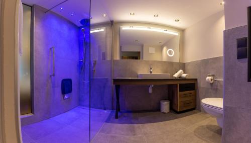 a bathroom with a sink and a shower with purple lighting at Appartements zum Strossna in Mayrhofen