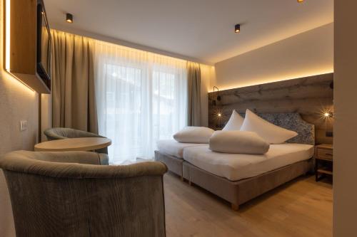 a hotel room with two beds and a chair at Appartements zum Strossna in Mayrhofen
