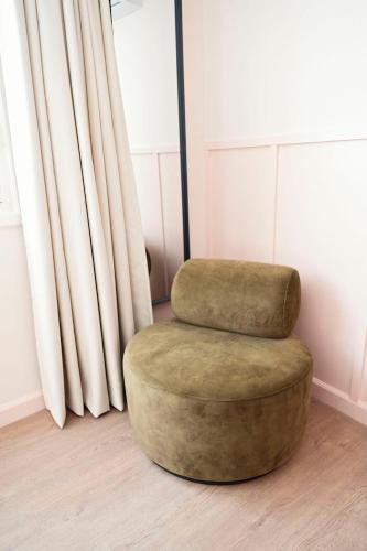 a green ottoman sitting in a room with curtains at The Times Hotel in Amsterdam
