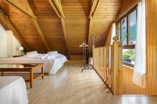 a bedroom with two beds and a wooden ceiling at Alojamiento Escarrilla Pirineos in Escarrilla