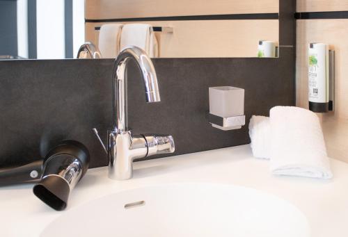 a sink with a faucet and a roll of paper towels at TU Hotel by WMM Hotels in Tuningen