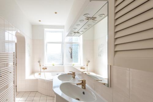 a white bathroom with two sinks and a mirror at Haus Decker, App 2 in Wenningstedt