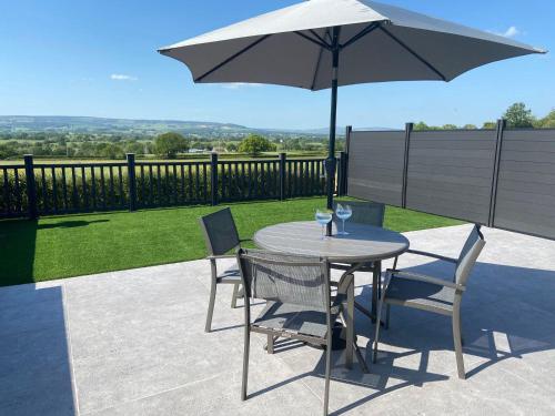 a table and chairs with an umbrella on a patio at ViewLangho in Blackburn