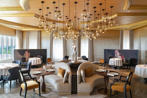 a dining room with tables and chairs and chandeliers at Royal Champagne Hotel & Spa in Champillon