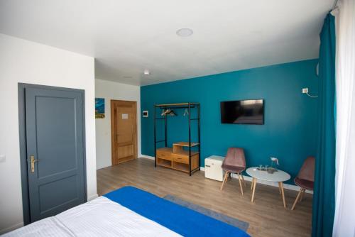 1 dormitorio con pared azul, cama y mesa en English House, en Bistriţa