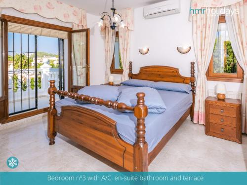 een slaapkamer met een houten bed en een raam bij Villa Talia by HMR Holidays Moraira in Moraira