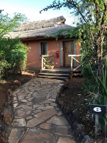 a small house with a thatched roof and a walkway at Escarpment Luxury Lodge Manyara in Mto wa Mbu