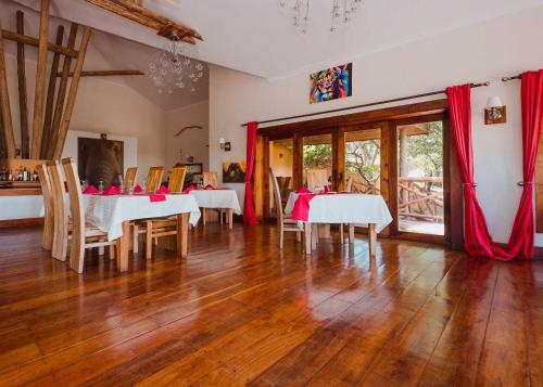 a dining room with white tables and chairs and red curtains at Escarpment Luxury Lodge Manyara in Mto wa Mbu