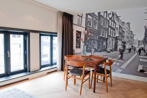 a living room with a table, chairs and a painting on the wall at Hotel IX Nine Streets Amsterdam in Amsterdam