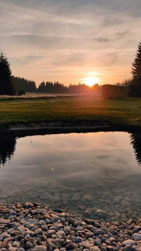 a sunset over a body of water with the sun setting at Maringotka Gerlovka Šumava in Čachrov