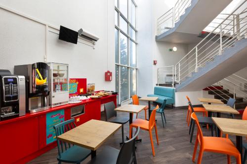 a restaurant with wooden tables and chairs and stairs at hotelF1 Longwy in Longwy