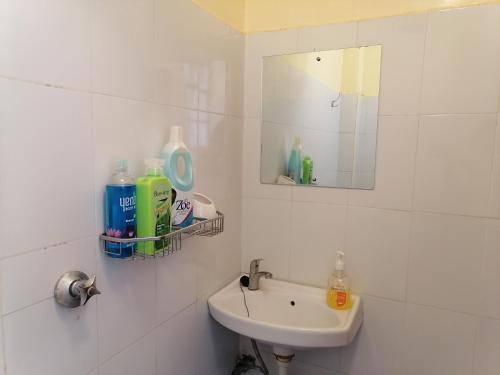 Baño blanco con lavabo y espejo en Lovely One bedroom Apartment , TRM Drive Nairobi, en Nairobi