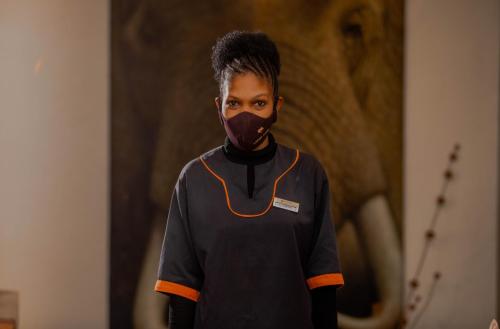 a man wearing a mask with an elephant in the background at Escarpment Luxury Lodge Manyara in Mto wa Mbu