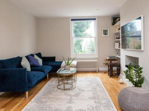 a living room with a blue couch and a table at Pass the Keys Immaculate flat with roof terrace in North London in London