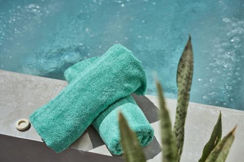 a green towel sitting next to a swimming pool at Meltemi Excelsior Suites in Perissa