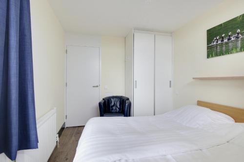 a bedroom with a white bed and a blue curtain at DE TRINTEL met zeezicht in Egmond aan Zee