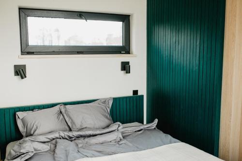 a bed with a green headboard and a window at Birštonas Tiny Hemp House in Birštonas