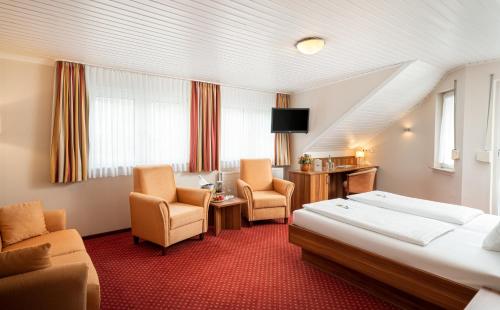 a hotel room with a bed and two chairs at Hotel Pistono in Dieblich