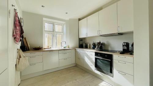 cocina blanca con armarios blancos y ventana en ApartmentInCopenhagen Apartment 1461 en Copenhague