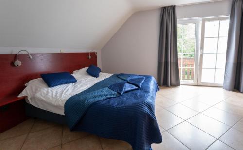 a bedroom with a bed with blue pillows on it at Logement de Blauwe Reiger in Voeren