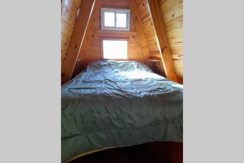 a bed in a tiny house with a window at Cabaña Pirayú in Oliveros